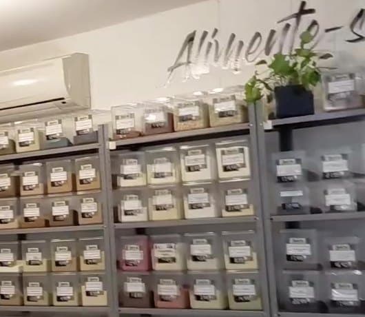 Parede da loja com o letreiro Alimente-se bem e as estantes de potes a granel
