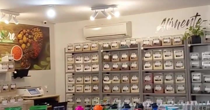 Salão da Amore: estantes de aço com potes de granel, o letreiro Alimente-se bem na parede e a gôndola de produtos na frente